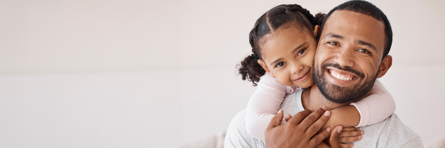 Smiling father and young daughter hugging, ready for back-to-school dental checkup